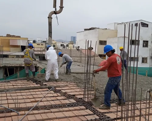 Proceso de construcción de vivienda bifamiliar en San Borja, Lima, con trabajadores realizando vaciado de losa de concreto, proyecto desarrollado por Arqbimstudio especialistas en diseño y construcción de casas modernas en Perú.